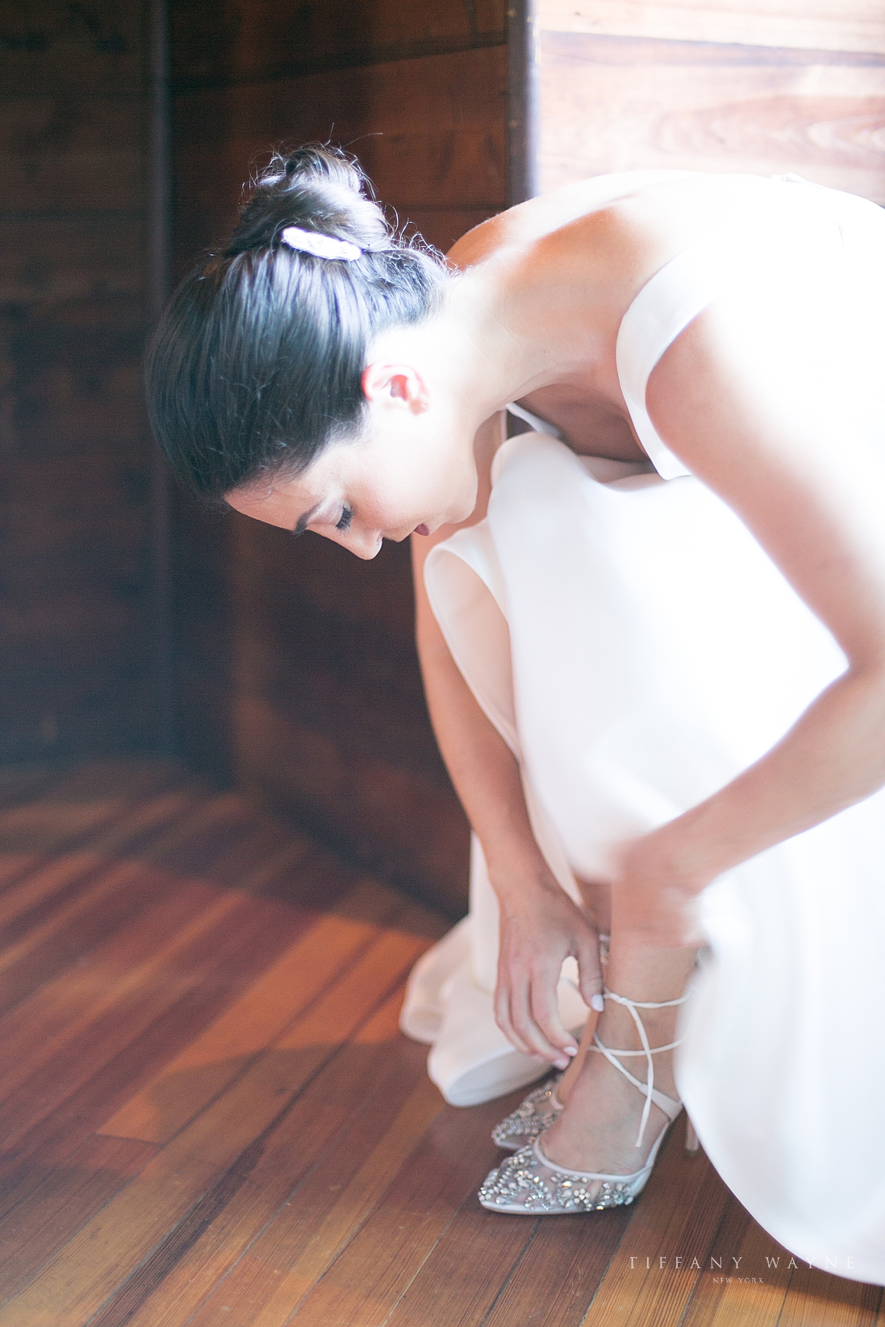 bride puts on shoes at Lake George Club captured by wedding photographer Tiffany Wayne